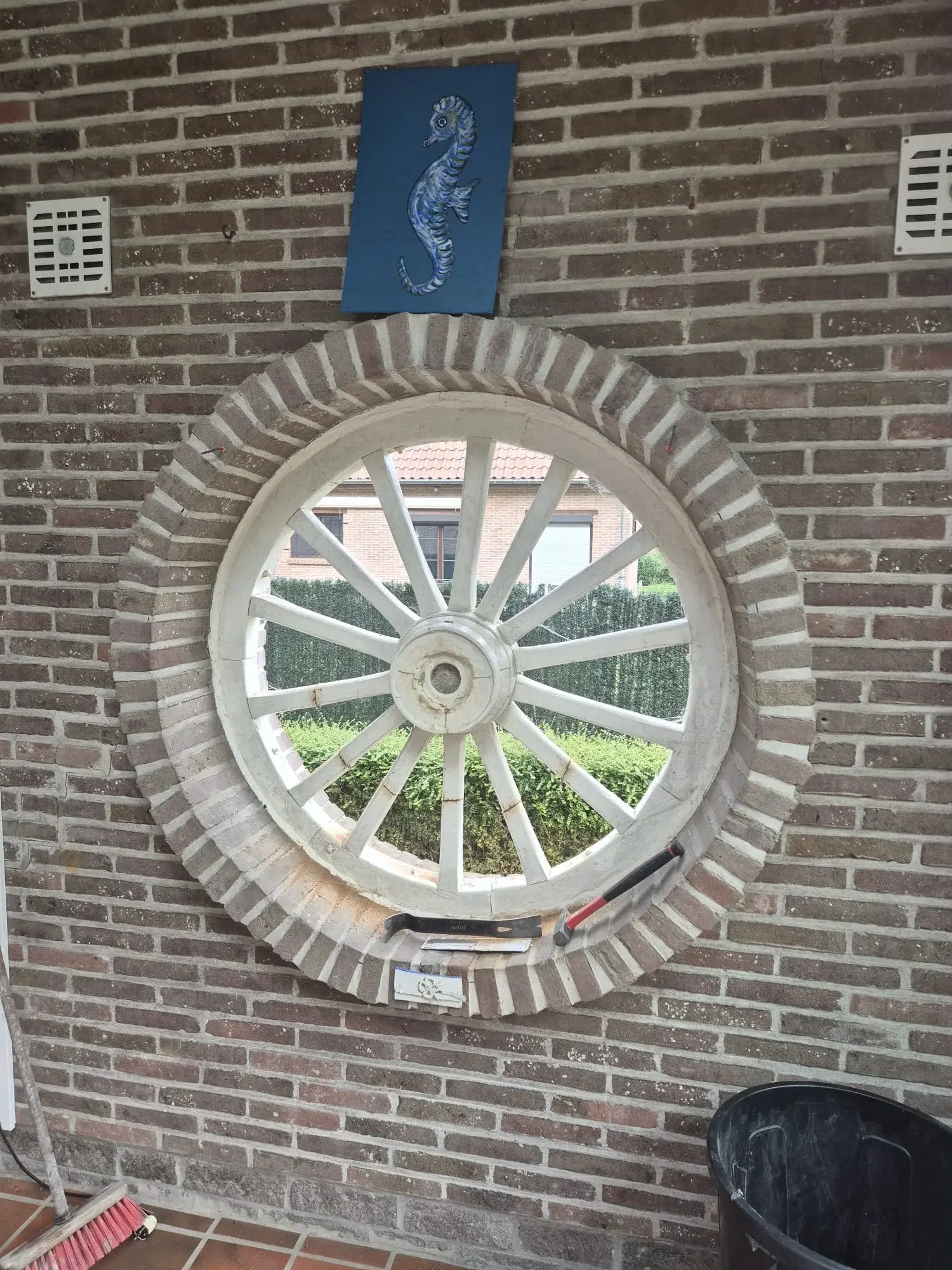 Ancienne fenêtre ronde à rayons dans son encadrement de briques avant remplacement