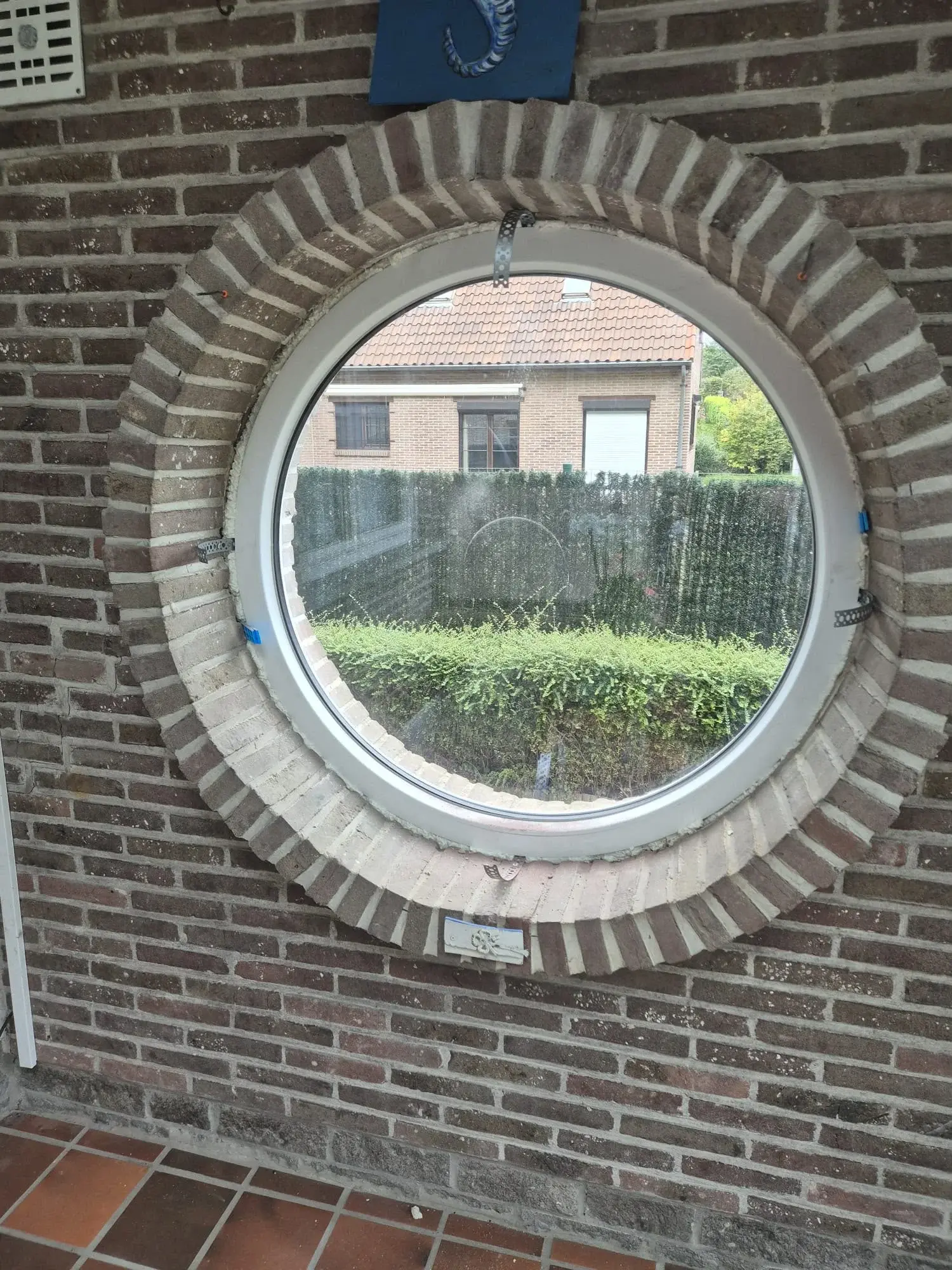 Nouveau châssis rond fabriqué sur mesure en cours de fixation dans la maçonnerie