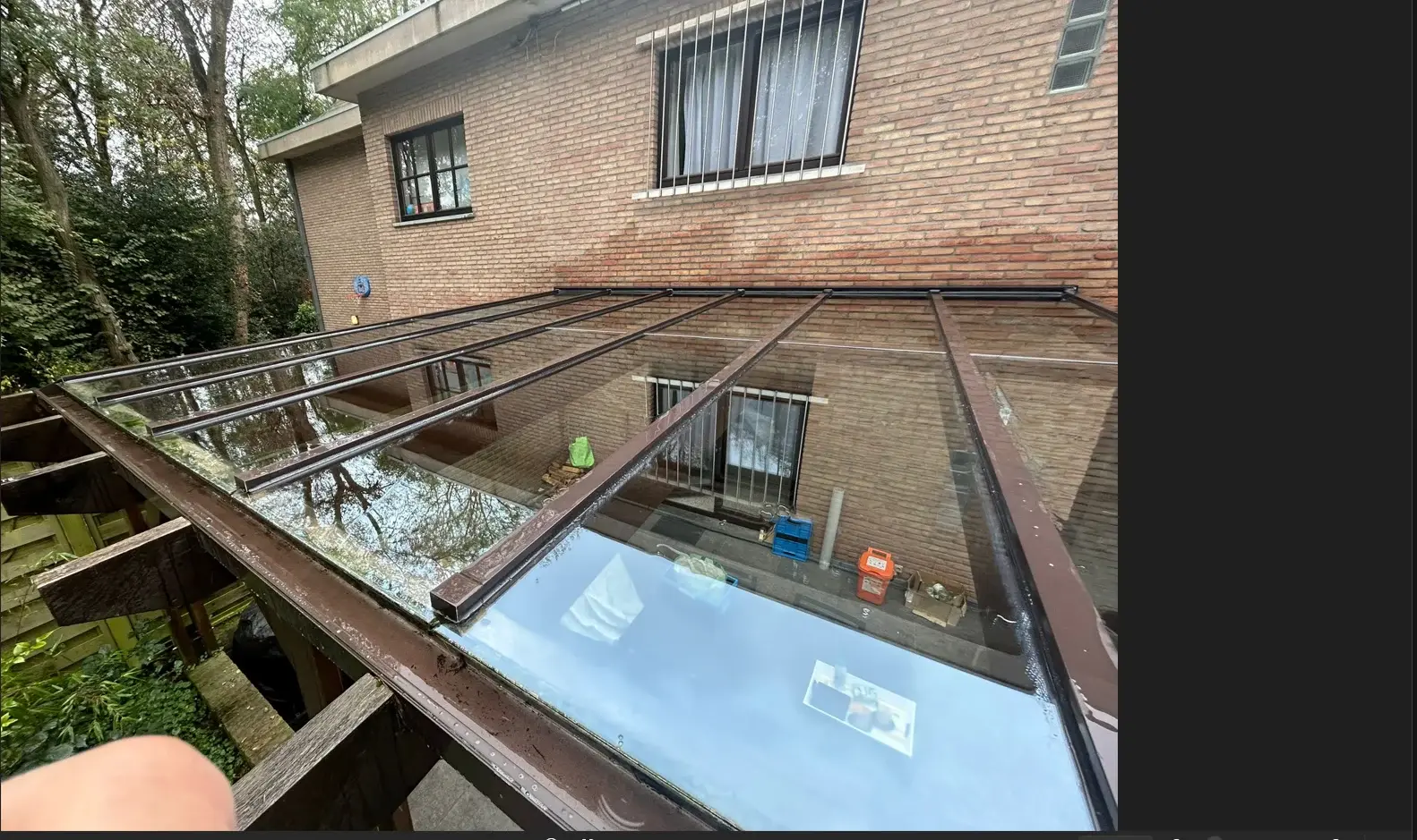 Toiture vitrée à profilés bruns raccordée à une façade en briques sur un chantier de réparation