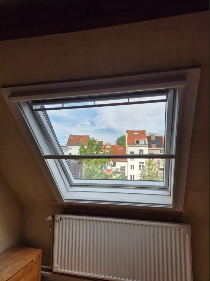 Fenêtre de toit vue depuis les combles avec sa moustiquaire devant l’ouverture