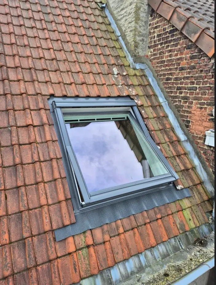 Fenêtre de toit posée vue de l’extérieur avec ses raccords dans la toiture en tuiles
